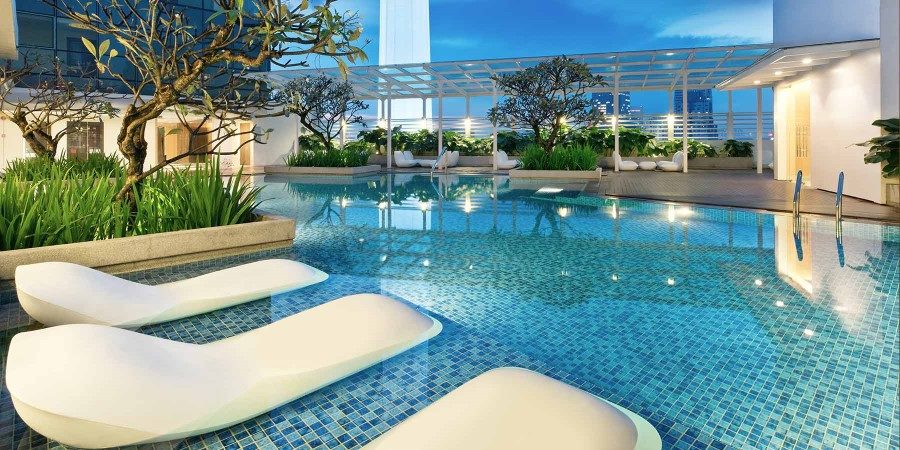 The hotel features a swimming pool encircled by flourishing plants, offering a peaceful retreat for guests.